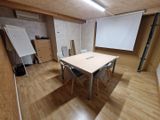 une salle équipée d'une table, de chaises et d'un écran de projection