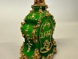 a green and gold clock sitting on a white surface