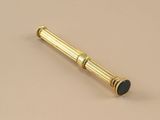 an image of a gold pen with a black tip on a beige surface