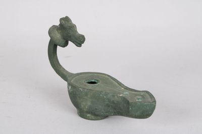 a green statue of a giraffe with a flower on it ' s head