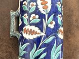 un vase bleu et blanc orné de fleurs, posé sur un support marron