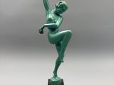 Une statue représentant une femme en robe verte se dresse sur un socle noir.