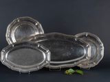 three silver trays sitting on top of each other next to a leaf