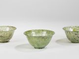 trois bols en verre vert posés l'un à côté de l'autre sur une surface blanche