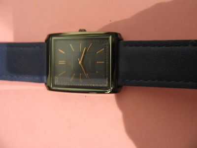 une montre noire et dorée montée sur un bracelet en cuir noir
