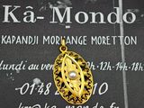 un pendentif en or orné d'une perle, posé sur une plaque