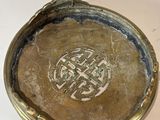 a small silver plate with a design on it