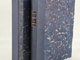 an old book with a blue cover sitting on top of a white table
