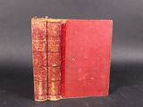 an old red book sitting on top of a table next to a black background