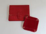 une paire de sacs à main en cuir rouge posés sur une surface blanche
