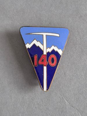 une image représentant un pin's orné d'un triangle bleu et blanc sur lequel figure le chiffre 140
