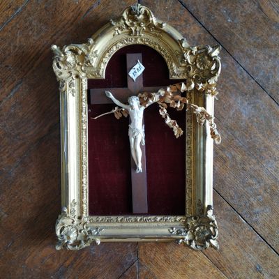 un crucifix dans un cadre doré posé sur un plancher en bois