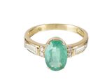 un gros plan d'une bague en or sertie d'une émeraude ovale et de pierres taillées en baguette