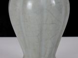 a white vase sitting on a table with a black background