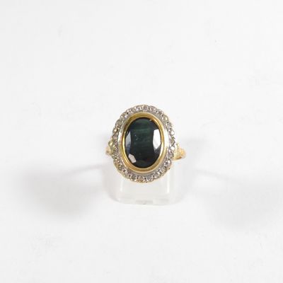 une image d'une bague en or avec une pierre verte entourée de diamants
