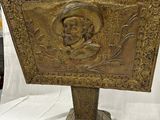 une photo d'une plaque en bois sur laquelle figure le portrait d'un homme