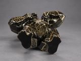 a small piece of black and gold stone on a gray surface