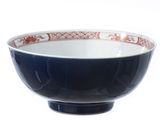 un bol noir orné d'un motif rouge et blanc