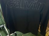 a person standing next to a black t - shirt with the word calvin on it