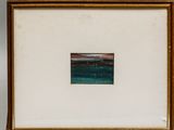 two framed pictures of a beach and a body of water in a wooden frame