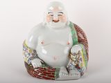 une statue représentant un Bouddha souriant assis sur une chaise