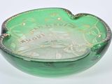 a green glass bowl with writing on it on a white surface
