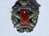 a silver and red badge on a white surface