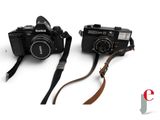 two cameras sitting next to each other on a white surface