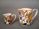 two pieces of pottery with floral designs on them on a gray surface