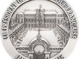 an image of a silver medal with a picture of a palace