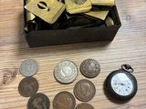 une boîte de pièces de monnaie et une montre de poche posées sur une table