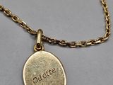 un gros plan d'un collier plaqué or sur lequel est gravé le mot « odalate »