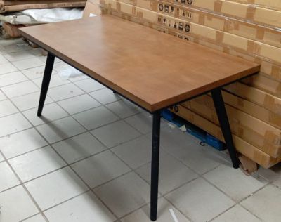 une table en bois aux pieds noirs posée sur un sol carrelé