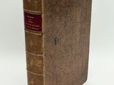 an old book sitting on top of a white table next to a purple thread