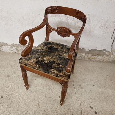 une chaise en bois dont l'assise est recouverte d'un tissu noir et marron