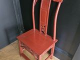 une chaise rouge posée sur un parquet, devant un mur noir
