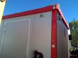 a red and white portable toilet sitting in the middle of a yard