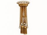une image représentant une broche en or ornée de perles et de pompons