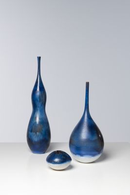 trois vases bleus posés sur une table blanche