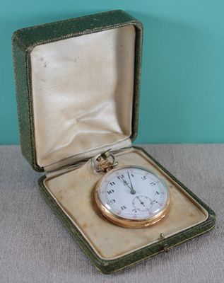 a gold pocket watch in a case on a table