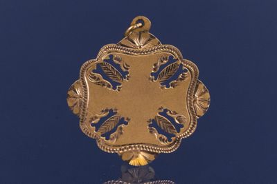 un pendentif en or orné d'un motif sur un fond bleu