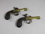 deux revolvers anciens en laiton posés sur une surface blanche