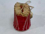 a red vase with a rope wrapped around it sitting on a white surface