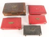 six red and black boxes with brass handles on a white surface