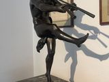 statue of a man holding a rifle in a room with a framed picture on the wall