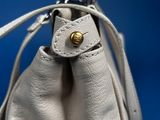 leather handbag on a blue background with a gold button