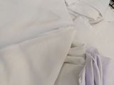 a pile of folded white shirts on a bed