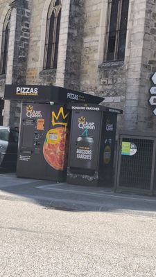 un homme qui roule à vélo dans la rue, devant une pizzeria