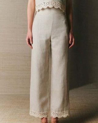 an image of a woman standing in front of a wall wearing a white top and pants