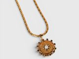 a gold necklace with a sunflower pendant on a chain